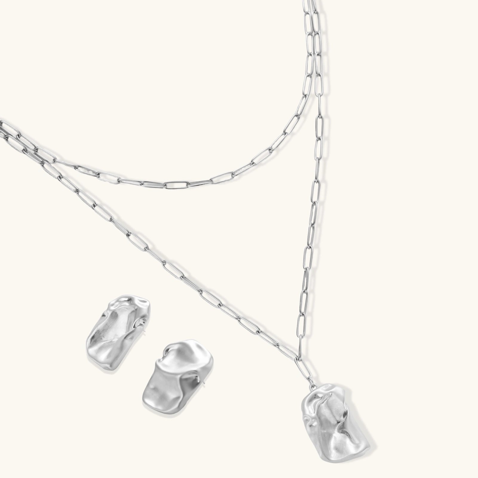 Modern textured hoop earrings and layered chain necklace with liquid metal pendant in silver and gold finishes.