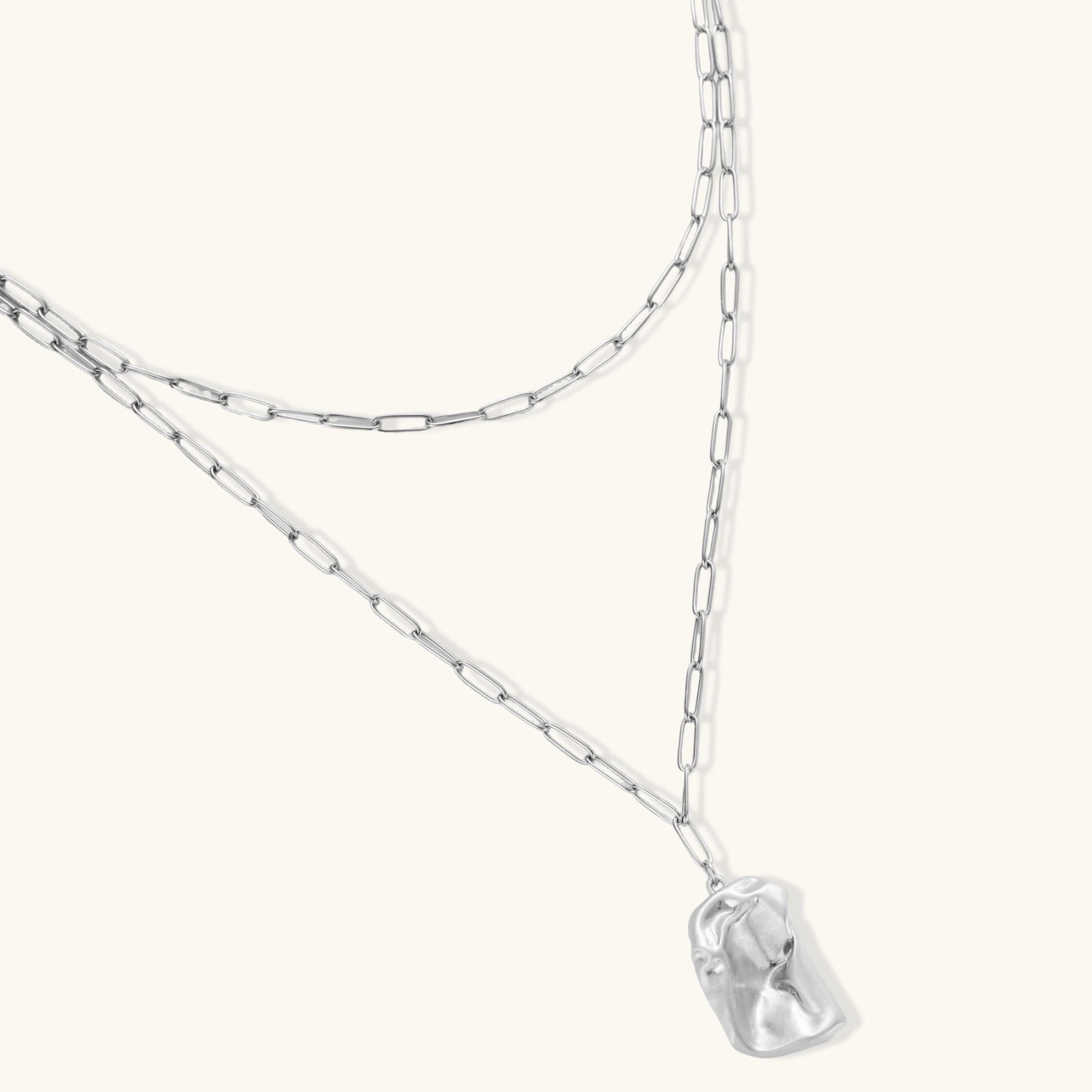 Modern textured hoop earrings and layered chain necklace with liquid metal pendant in silver and gold finishes.
