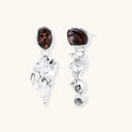 Abstract sculptural silver earrings with brown resin stones featuring organic fluid metalwork design on white background.