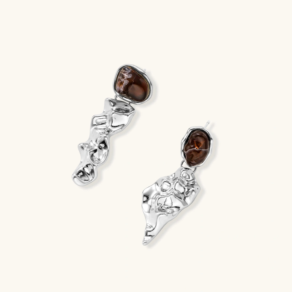 Abstract sculptural silver earrings with brown resin stones featuring organic fluid metalwork design on white background.